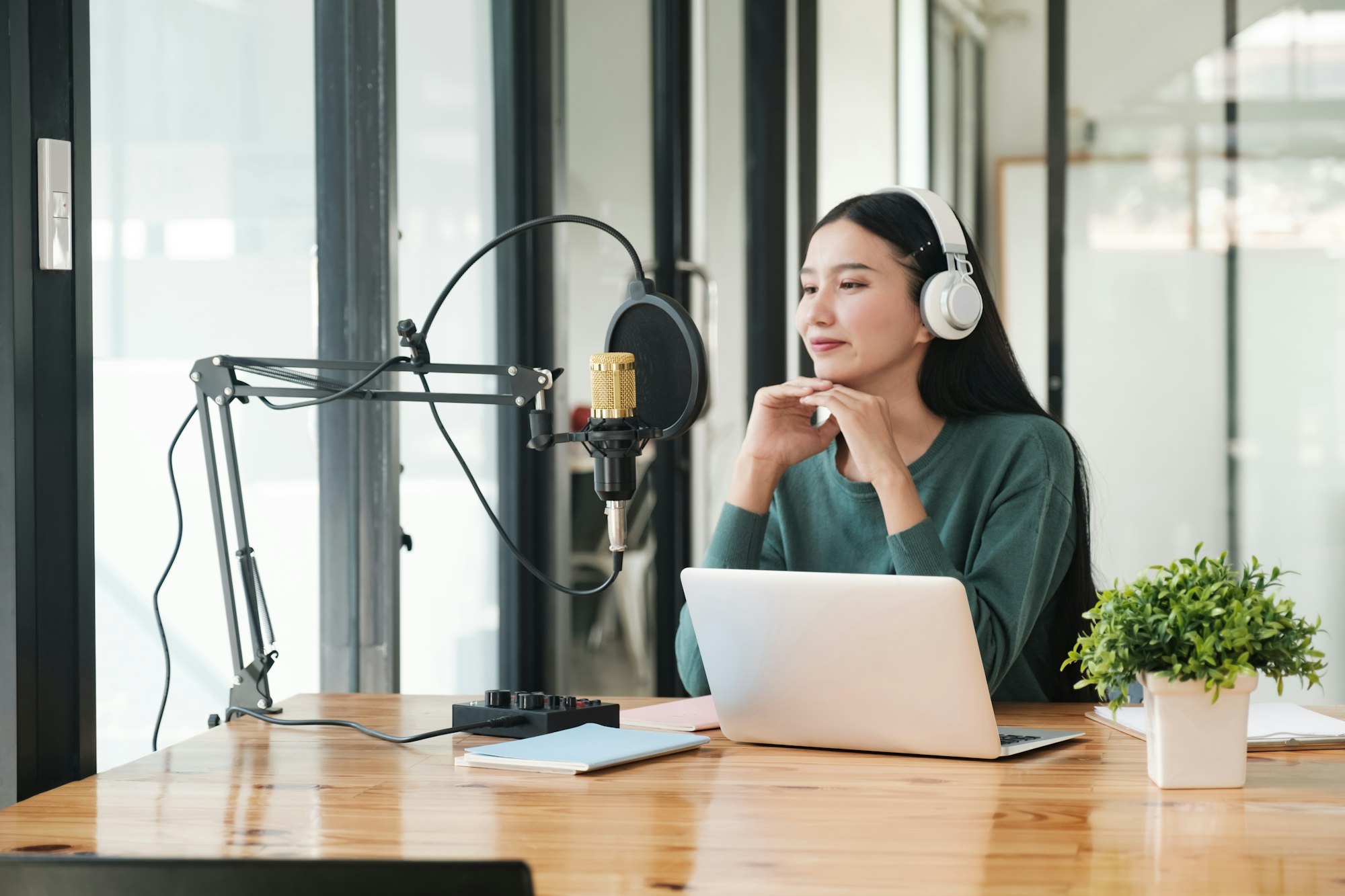 A woman is sitting at a desk with a microphone and a laptop